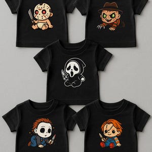 May include: Five black short-sleeve t-shirts featuring cartoon horror character graphics. The designs include a hockey-masked figure with a knife, a clawed figure in a fedora, a hooded ghost figure, a masked figure in overalls, and a doll in overalls.