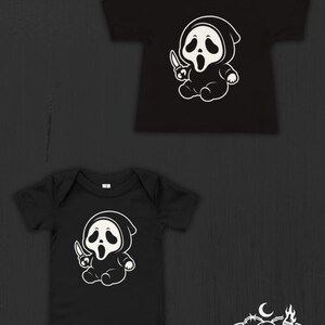 May include: A black short-sleeved t-shirt and a black short-sleeved bodysuit, both featuring a white graphic of a cartoon character in a hooded robe holding a knife. The bottom right corner displays a white logo with a skull and the text Nocturnal Nursery Co.