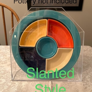 May include: A turquoise ceramic serving platter with a divided design, featuring sections in yellow, orange, cream, and navy blue. The platter is encased in a clear acrylic display case. The text "Pottery not included" and "Slanted Style" are visible.