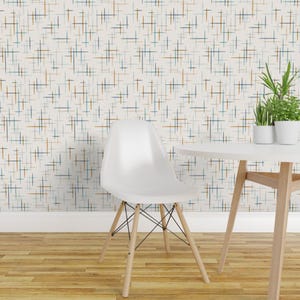 May include: A white molded plastic chair with a curved back and wooden legs stands before a wall covered in wallpaper featuring a repeating pattern of thin, intersecting horizontal and vertical lines in shades of blue, orange, and dark gray.
