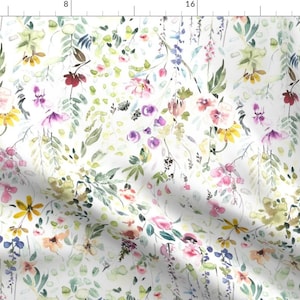 May include: A white fabric featuring a watercolor floral pattern with scattered pink, yellow, purple, and dark red blossoms interspersed with green foliage and thin stems. The design is printed across the textile surface with a ruler visible.