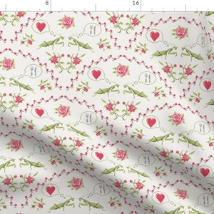 May include: A white fabric with a repeating pattern of green praying mantises, red hearts, and pink roses. The mantises are holding forks and knives in their hands. The hearts are in thought bubbles.