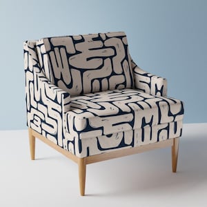 Op de afbeelding: Een fauteuil met een donker marineblauw en gebroken wit abstract patroon van onderling verbonden, gebogen vormen. De stoel heeft een vierkante rugleuning, een gevoerde zitting en vier taps toelopende lichtgekleurde houten poten.