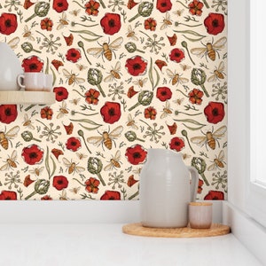 May include: A cream-colored wallpaper with a repeating pattern of red poppies, green leaves, and small brown bees. The wallpaper is shown in a kitchen setting with a white pitcher and a small brown jar on a wooden coaster.