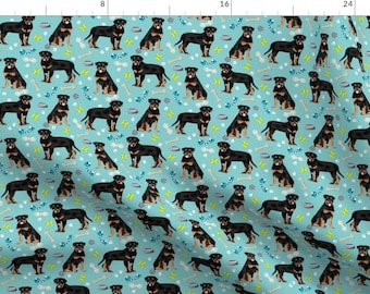 Könnte beinhalten: Ein nahtloses Muster mit schwarzen Rottweiler-Hunden auf hellblauem Hintergrund. Die Hunde sind in verschiedenen Posen, darunter stehend, sitzend und laufend. Das Muster enthält auch kleine, wiederholte Bilder von Hundeknochen, Hundenäpfen und Tennisbällen.