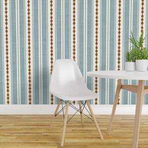 May include: Wallpaper featuring a vertical pattern of alternating light blue stripes, thin white lines, and brown beaded columns. A white molded chair with light wooden legs and a white round table with two small green potted plants are in front.