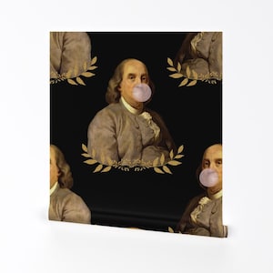 Puede incluir: Un patrón de papel tapiz negro y dorado con una imagen repetida de Benjamin Franklin soplando una burbuja. El fondo es negro con acentos de pan de oro.