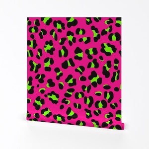 Puede incluir: Un rollo de papel pintado con un fondo rosa vibrante y un patrón repetido de manchas de leopardo negras y verde neón. El diseño es audaz y llamativo, adecuado para una pared de acento.