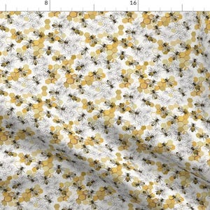 May include: A fabric pattern featuring a repeating design of bees, honeycombs, and floral elements. The bees are depicted in black and yellow, while the honeycombs are in shades of yellow and gold. The floral elements are in a light gray color, all set against a white background.