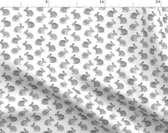 May include: A white fabric with a repeating pattern of gray watercolor bunnies. The bunnies are all facing the same direction and are arranged in a grid pattern.