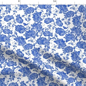 May include: A white fabric with a blue floral pattern. The flowers are stylised and have a vintage look. The fabric is perfect for crafting, quilting, or making home decor.