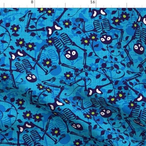 May include: A blue fabric with a repeating pattern of skeletons in a yoga pose with flowers and vines. The skeletons are dark blue and the flowers are green and blue.