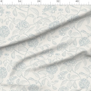 May include: Off-white fabric with a repeating pattern of blue-grey hydrangea flowers and leaves. The design features detailed line drawings of the floral elements, creating a delicate and elegant aesthetic. The fabric is likely suitable for various craft and home decor projects.
