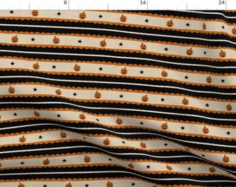 May include: Fabric featuring a repeating pattern of small orange jack-o'-lanterns and black stars arranged on horizontal cream-colored bands. The bands are bordered by scalloped orange edges and separated by thin black and white stripes.