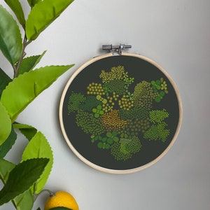 May include: A circular embroidery hoop with a black background and a green and yellow floral design. The hoop is made of wood and has a metal screw on the top.