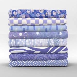 May include: A stack of eight fabric swatches in various shades of blue and white with different patterns, including floral, checkered, geometric, and abstract designs.