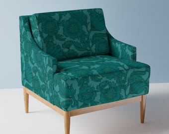 May include: A teal armchair with a floral pattern and wooden legs. The chair has a high back and a wide seat.