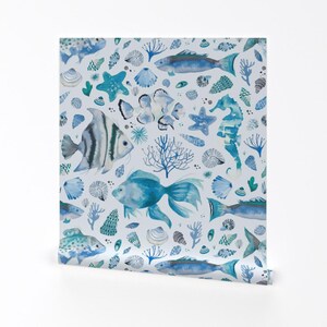 May include: A seamless pattern featuring blue and white watercolor illustrations of fish, seashells, coral, and starfish on a white background.