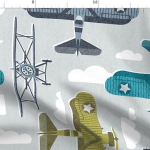 May include: A seamless pattern featuring a variety of vintage airplanes in shades of blue, green, and yellow against a light gray background with white clouds. The airplanes have stars on their wings and are flying in different directions.