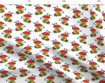 May include: A white background with a repeating pattern of red and white mushrooms with green frogs sitting under them.  There are blue flowers around the mushrooms.
