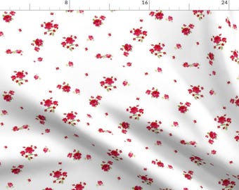 May include: White fabric with a repeating pattern of small red rose clusters. The roses are a deep red color with green leaves.