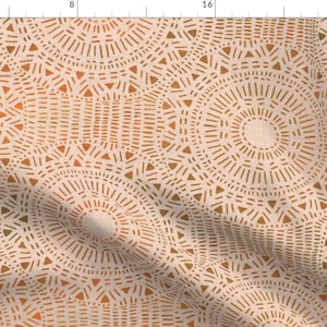 May include: Cream-colored fabric with a repeating pattern of circular designs. Each circle is composed of radiating lines and small triangles in shades of brown and orange, creating a textured effect.