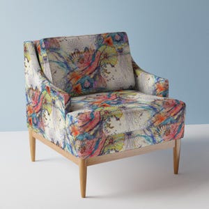 Könnte beinhalten: Ein bunter Sessel mit einem floralen Muster mit abstrakten Formen und Farben. Der Sessel hat einen hellen Holzrahmen und Beine.