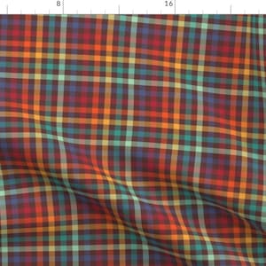 May include: A fabric with a plaid pattern in shades of red, orange, teal, yellow, and blue. The plaid design features intersecting lines creating a grid-like pattern. The fabric has a slightly textured appearance and a dark brown background.