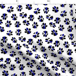 May include: White fabric with a repeating pattern of blue and black paw prints. Each paw print has a thin blue line across it.