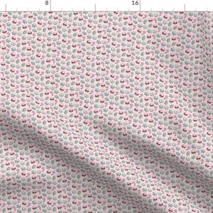 May include: A pink fabric with a repeating pattern of green and red Christmas-themed shapes. The shapes include candy canes, holly leaves, ornaments, and stars.