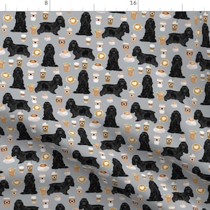 May include: A seamless pattern featuring black American Cocker Spaniels and coffee cups on a light gray background. The dogs are in various poses, some sitting, some standing, and some looking at the viewer. The coffee cups are filled with coffee and have a brown and white design.