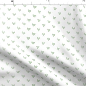 Puede incluir: Una tela blanca con un patr&oacute;n repetido de corazones verde claro. Los corazones est&aacute;n dibujados a mano y tienen una forma ligeramente irregular.