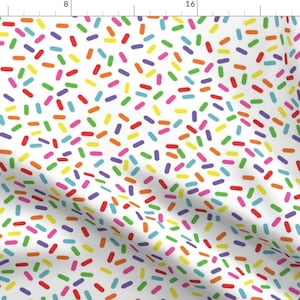 May include: A white background with a repeating pattern of colorful sprinkles. The sprinkles are in various shades of red, orange, yellow, green, blue, and purple.