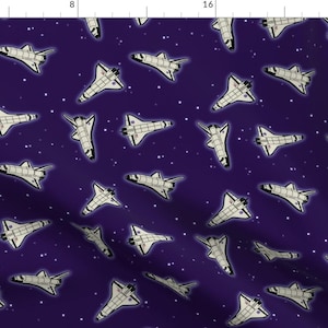 May include: A repeating pattern of white space shuttles on a dark purple background with white stars.