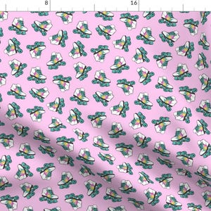 May include: A pink fabric with a repeating pattern of white roller skates with rainbow colored wheels. The skates are outlined in teal.