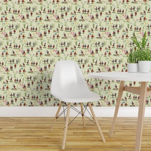 May include: Wallpaper featuring a repeating pattern of red ladybugs and small insects on a light green background, displayed behind a white molded plastic chair with wooden legs and a round white table holding two potted green plants.