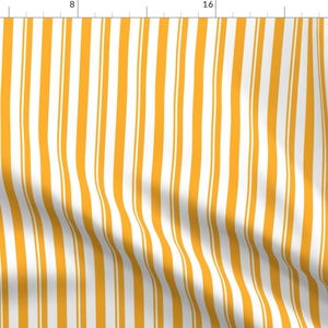 May include: White and yellow striped fabric with a subtle wave pattern. The fabric is a woven cotton blend.