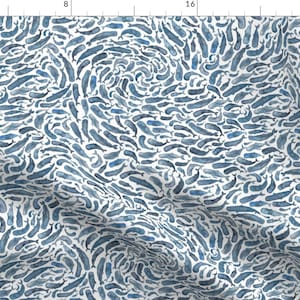 以下が含まれることがあります： さまざまなサイズの青い水彩のクジラが繰り返しパターンで描かれた白い生地。クジラは渦巻き状に配置されています。