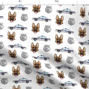 May include: A white background with a repeating pattern of German Shepherd dog heads, police cars, and police badges. The dog heads are brown and have their tongues sticking out. The police cars are white with blue accents. The police badges are silver with the words "Police" on them.