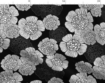 Op de afbeelding: Zwart-wit bloemenpatroon met gestileerde bloemen op een zwarte achtergrond. De bloemen zijn wit omrand en hebben een gestippeld patroon in de binnenkant.