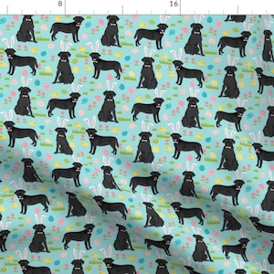 May include: A seamless pattern featuring black Labrador Retriever dogs wearing bunny ears on a light blue background with colourful Easter eggs.