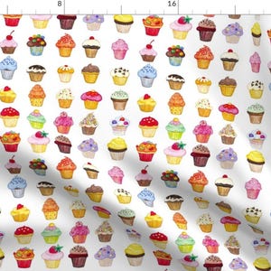 以下が含まれることがあります： 白い背景に、カラフルなカップケーキが繰り返しパターンで並んでいます。各カップケーキは、スプリンクル、チェリー、チョコレートチップなど、異なるフロスティングとトッピングが施されています。