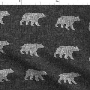 May include: A black and white fabric with a repeating pattern of white bear silhouettes. The bears are facing to the right.