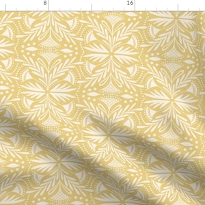 Op de afbeelding: Een naadloos patroon met een wit bloemenontwerp op een gele achtergrond. Het patroon bestaat uit herhalende geometrische vormen en ingewikkelde details.