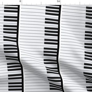 May include: A white fabric with three black and white piano key designs. The fabric is folded and has a slight wave pattern.