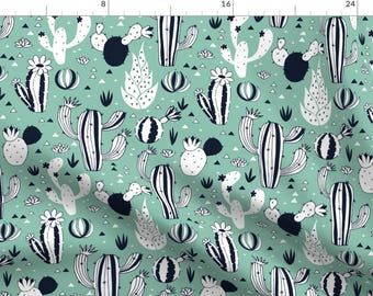 May include: A repeating pattern of cacti in white and navy blue on a light teal background. The design features various cactus shapes, including tall, spiky ones and rounder, segmented ones, with small white flowers and geometric shapes.