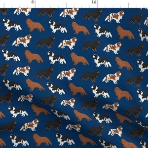 May include: Navy blue fabric featuring a repeating pattern of Cavalier King Charles Spaniel dogs in various colors. The dogs are depicted in brown, black, and white, creating a playful and charming design.