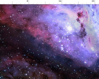 May include: A fabric print featuring a deep space nebula with vibrant purple, magenta, and blue gaseous clouds scattered with numerous bright white stars. A ruler along the top and left edges shows measurements in inches.