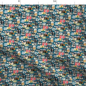 May include: A teal blue fabric with a repeating pattern of vintage cameras in various colours, including red, yellow, blue, and black.