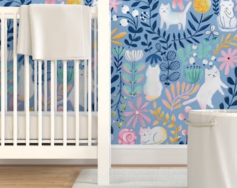 May include: A white crib with a white fitted sheet and a blue and white floral wallpaper with white cats. The wallpaper features a repeating pattern of flowers, leaves, and cats.